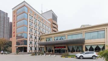A multi-story hotel with a modern facade, a covered entrance, and a parking area.