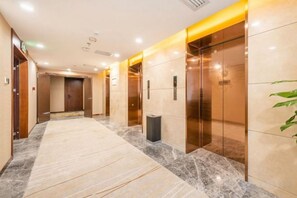 A hotel corridor with marble flooring, elevators, and a trash bin. - Nanyang Hotel, Jiaotong University, Xi'an (Jiaotong University Qinglong Temple) (Xi'an)