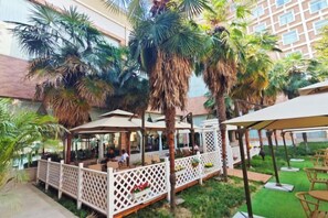 An outdoor patio area with seating arrangements and palm trees. - Nanyang Hotel, Jiaotong University, Xi'an (Jiaotong University Qinglong Temple) (Xi'an)