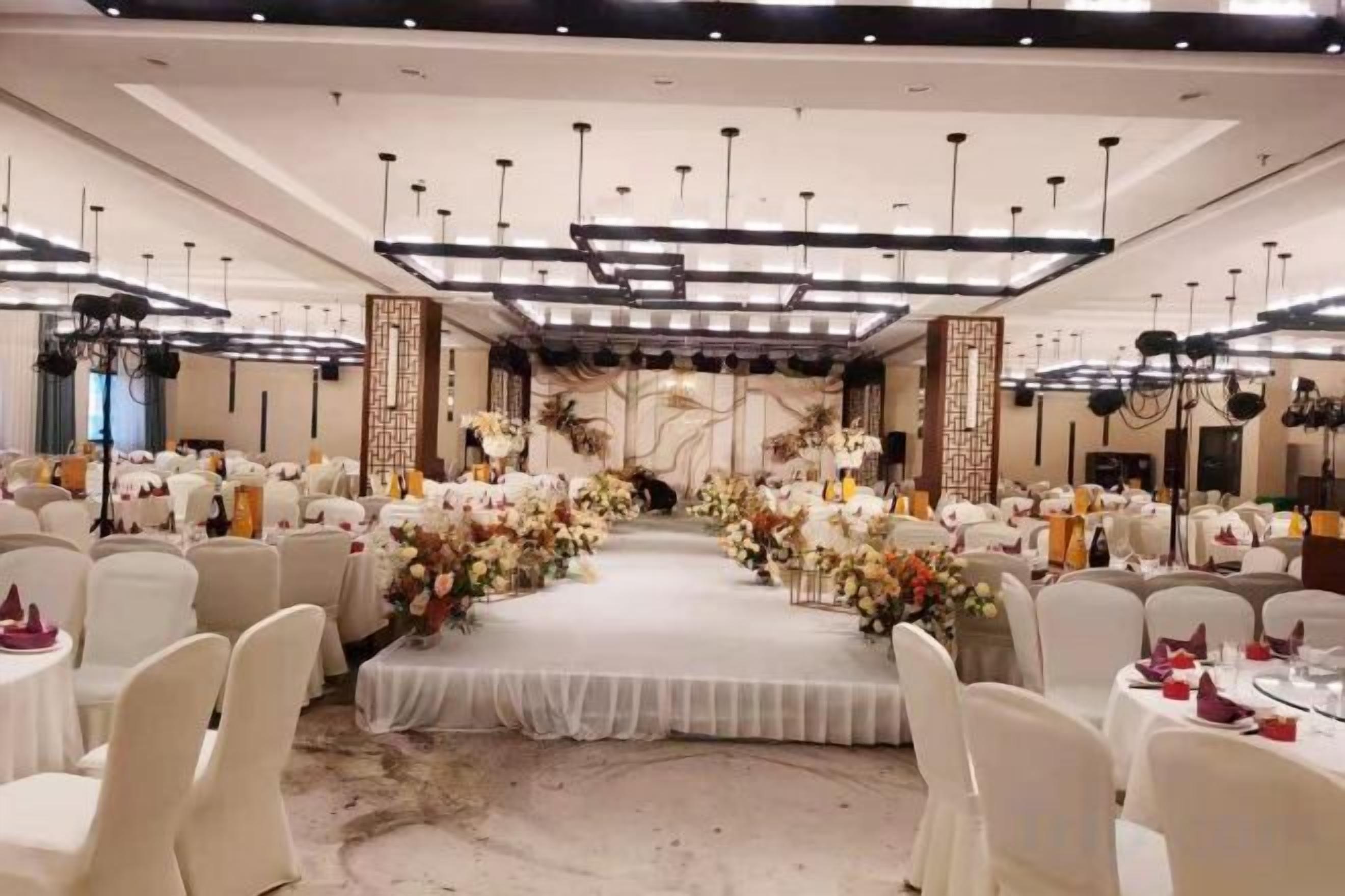 A banquet hall with a central stage, round tables, and chairs arranged for an event.