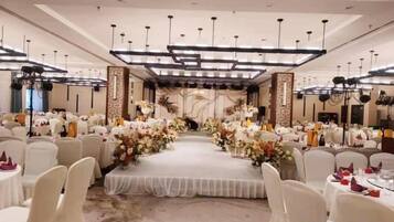 A banquet hall with a central stage, round tables, and chairs arranged for an event.