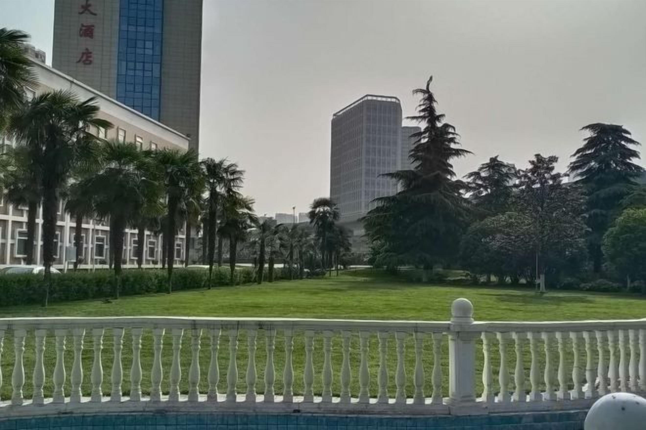 Een hotel met een modern gebouw, een verzorgd gazon en een witte hek.