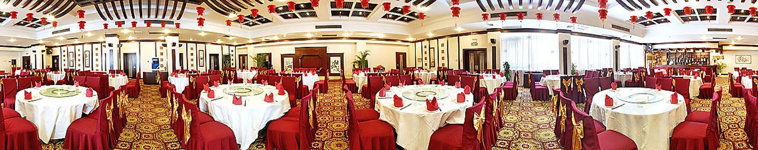 Une salle de banquet avec des tables rondes, des chaises rouges et un sol recouvert de moquette.