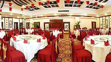 Une salle de banquet avec des tables rondes, des chaises rouges et un sol recouvert de moquette.