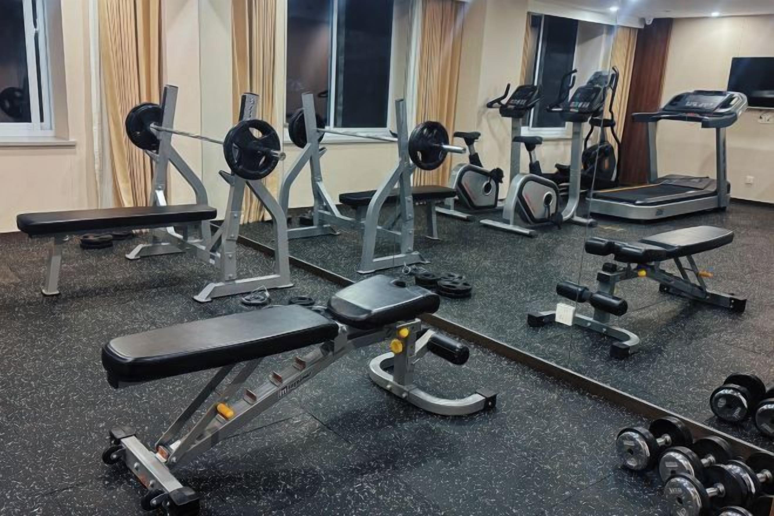 A gym with various exercise equipment including treadmills, weight machines, and free weights.