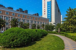 A building with a brick facade, a pathway, and green landscaping. - Nanyang Hotel, Jiaotong University, Xi'an (Jiaotong University Qinglong Temple) (Xi'an)