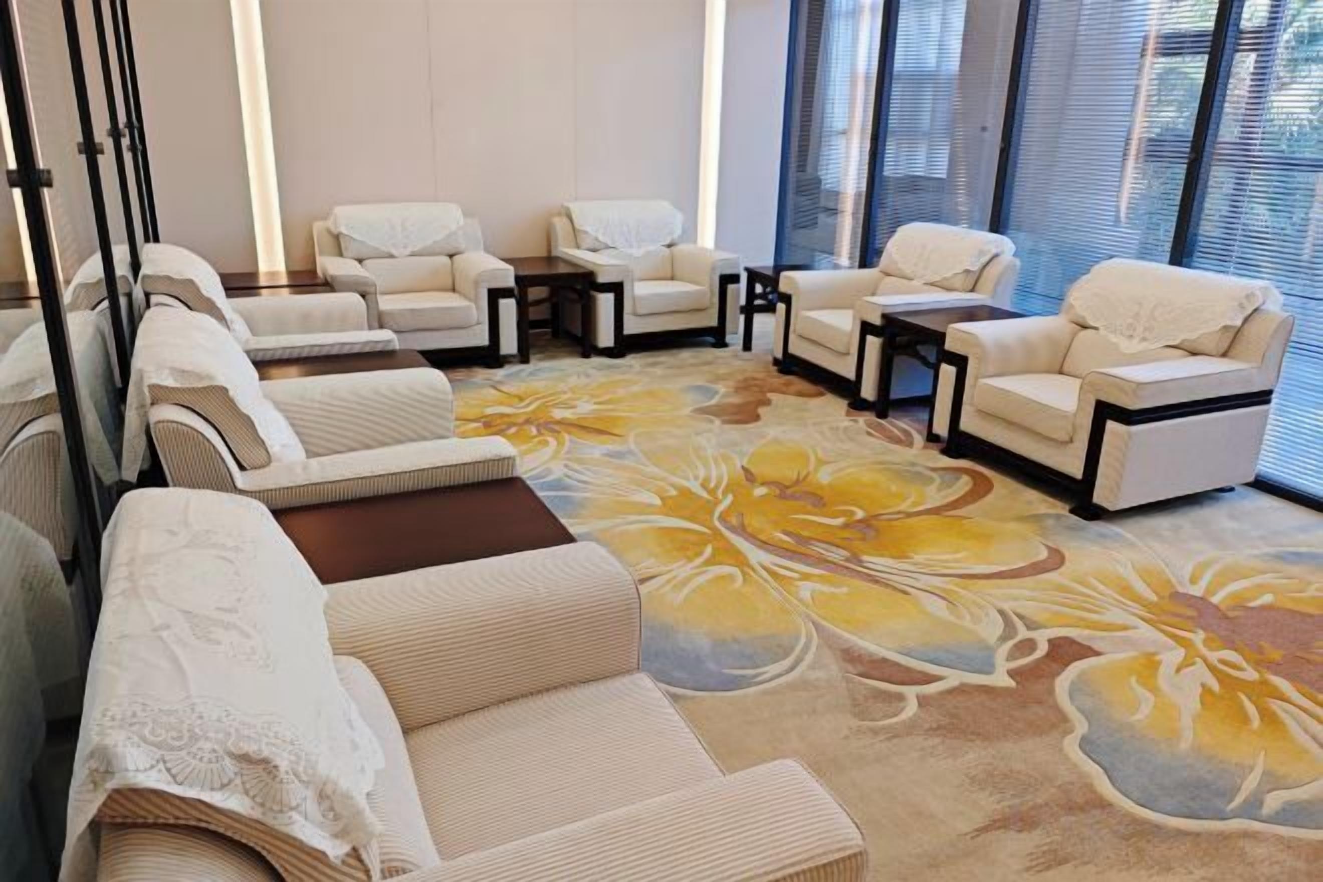 A room with multiple seating areas, including sofas and armchairs, arranged around a central table.