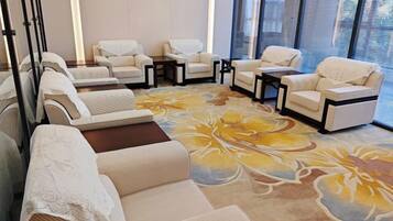 A room with multiple seating areas, including sofas and armchairs, arranged around a central table.