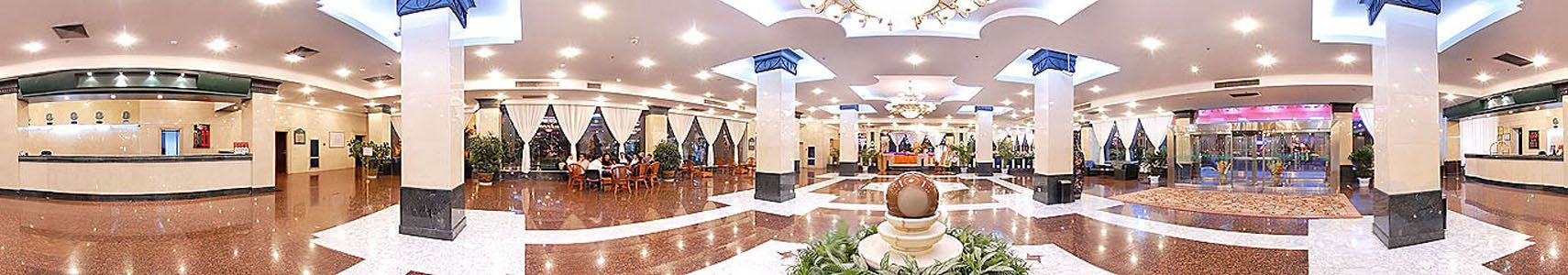 A spacious lobby with a reception desk, seating areas, and a central decorative fountain.