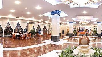 A spacious lobby with a reception desk, seating areas, and a central decorative fountain.