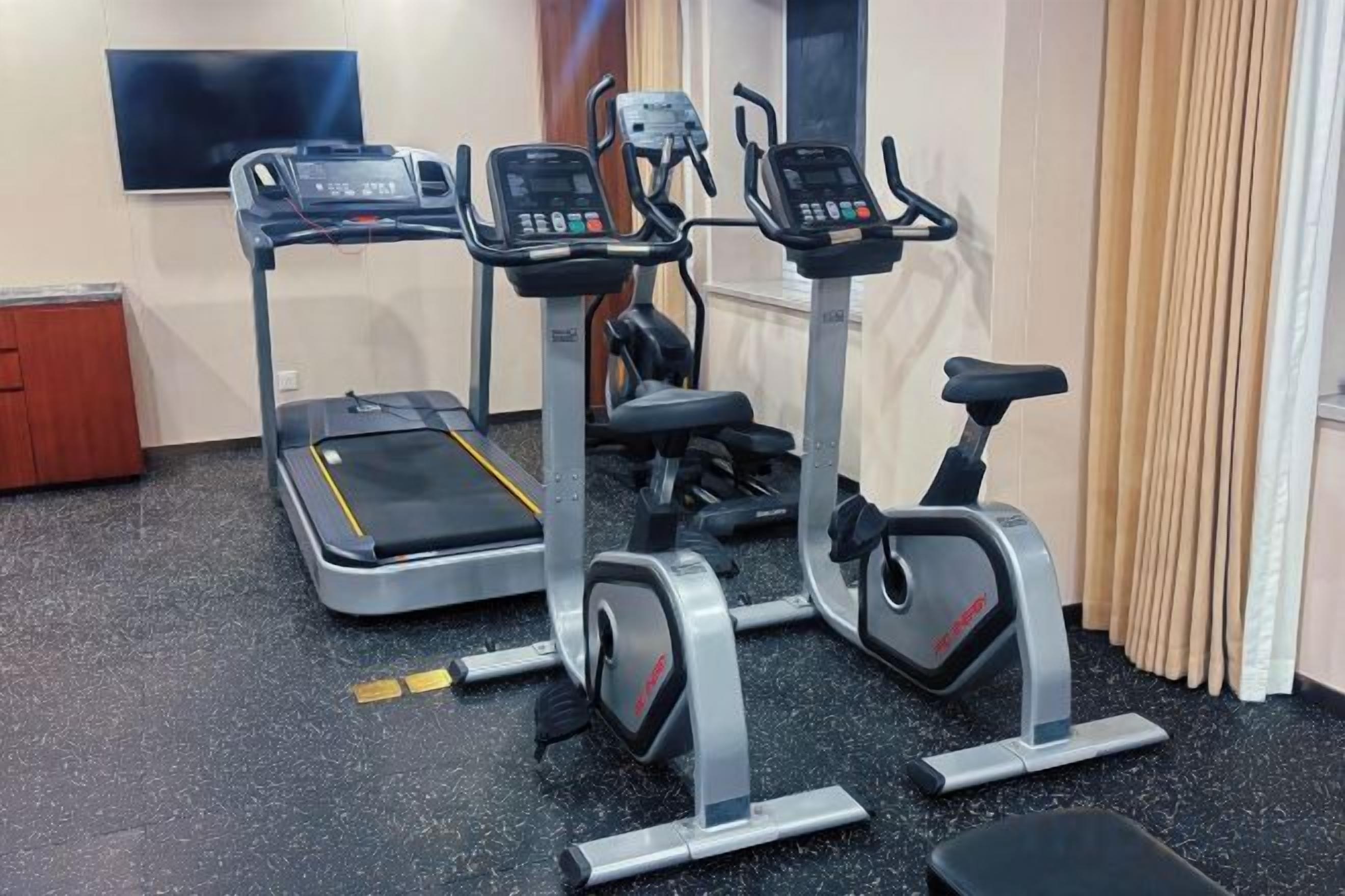Une salle de sport à domicile équipée de tapis de course, d’un vélo elliptique et d’un vélo d’appartement.