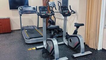 Une salle de sport à domicile équipée de tapis de course, d’un vélo elliptique et d’un vélo d’appartement.