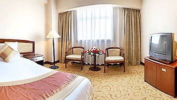 Une chambre d’hôtel avec un grand lit, un bureau avec une chaise, une télévision et une salle de bain.