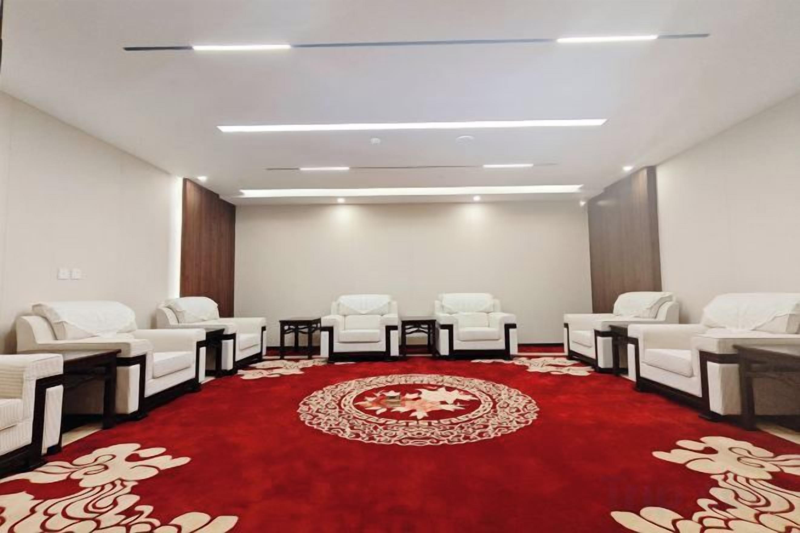 A conference room with a red carpet, white chairs, and tables.