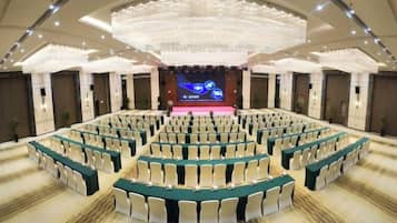 A large conference room with tiered seating and a stage at the front.