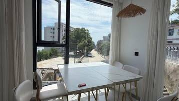 A room with a large window, a dining table, and chairs.