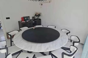 A round table with a black center surrounded by white chairs with black frames. - Wanghai Hotel (Fuding)