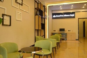 A hotel reception area with green chairs, a reception desk, and a sign for the Grand Tree Alliance Hotel. - GreenTree Alliance Hotel (Kunming Chuanjin Road Subway Station) (Kunming)