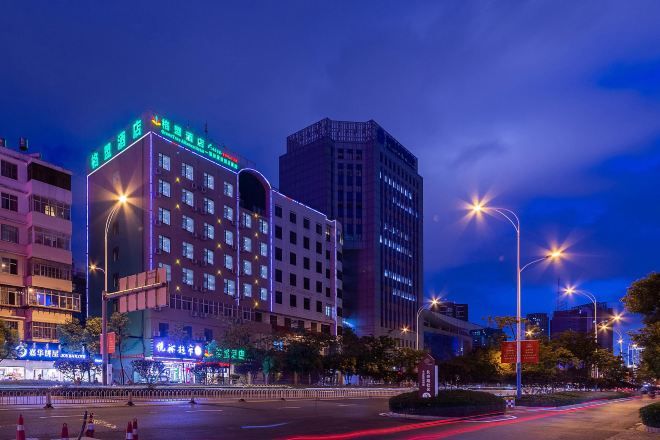 A multi-story hotel with illuminated signage, a well-lit street, and a clear view of the surrounding urban environment.