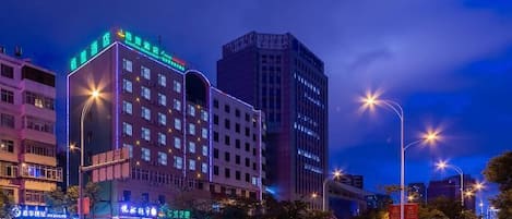 A multi-story hotel with illuminated signage, a well-lit street, and a clear view of the surrounding urban environment.