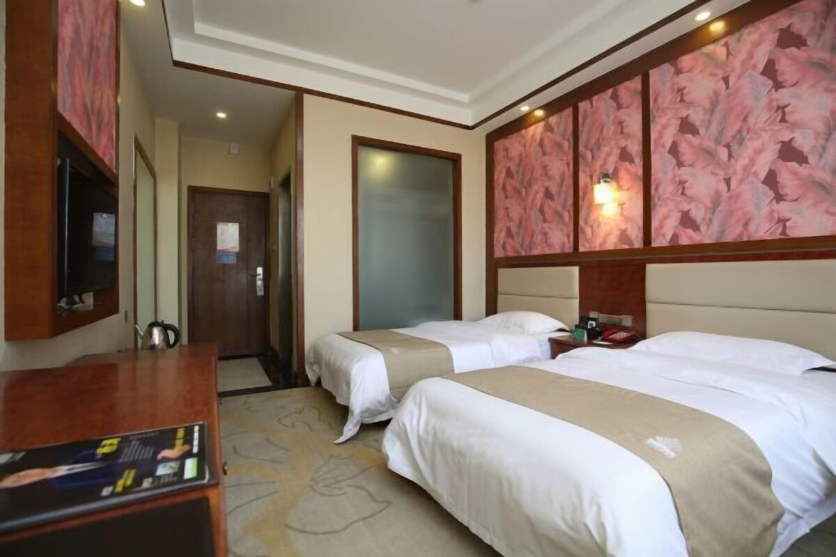 A hotel room with two beds, a desk with a computer, a television, and a minibar.