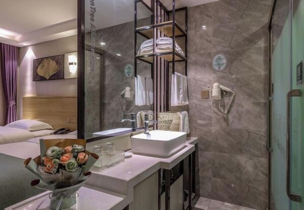 A modern bathroom with a large mirror, a white sink, and a shower area. There is a towel rack above the sink and a glass shower enclosure. - GreenTree Alliance Hotel (Kunming Chuanjin Road Subway Station) (Kunming)