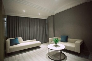 A modern living room with two sofas, a coffee table, and a large window with curtains. - Magnotel Hotel (Liye Baisanbon Shanghecheng Store) (Liyang)