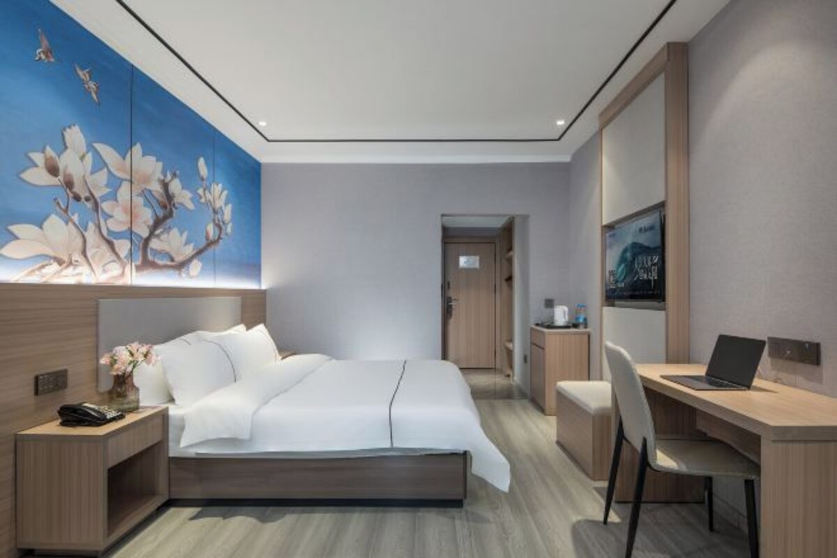 Une chambre d’hôtel moderne équipée d’un lit, d’un bureau et d’un ordinateur portable.