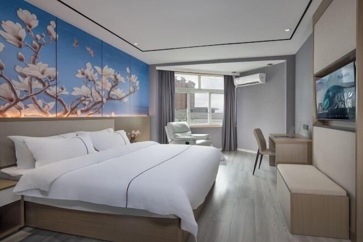 Une chambre d’hôtel moderne, dotée d’un grand lit, d’un bureau, d’une chaise et d’une grande fenêtre.