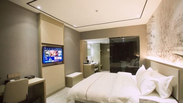 Quarto de hotel moderno com uma cama grande, uma escrivaninha e uma televisão.