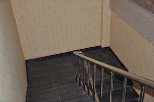 Una escalera con baldosas oscuras y barandilla de metal.