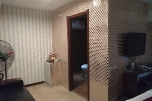Un baño con pared de azulejos, un inodoro, un lavabo y un ventilador.