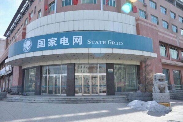 Un edificio con un letrero que dice "State Grid" y una estatua de león de piedra al frente.