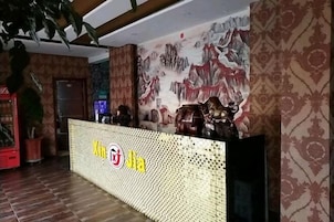 A reception area with a decorative counter, a wall with a mural, and patterned wallpaper.