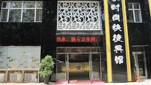 A building with a black facade and yellow accents, featuring a large sign with Chinese characters and a logo. - Hailin Xinjia Fashion Express Hotel (Hailin)