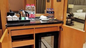 Une chambre d’hôtel équipée d’un minibar, d’un lit, d’une table de chevet et offrant une vue sur la pièce.