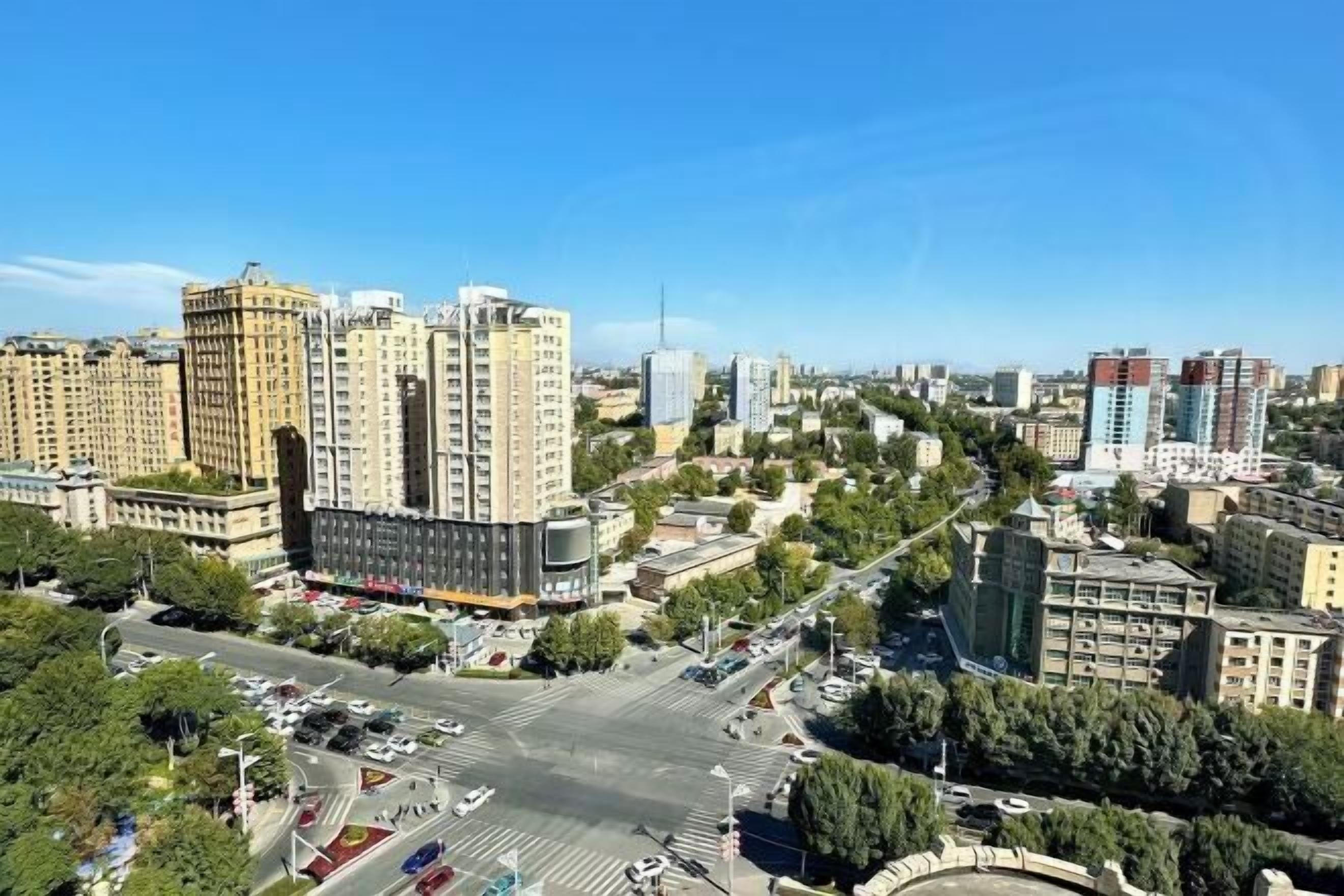 A cityscape with high-rise buildings, a central roundabout, and intersecting roads.
