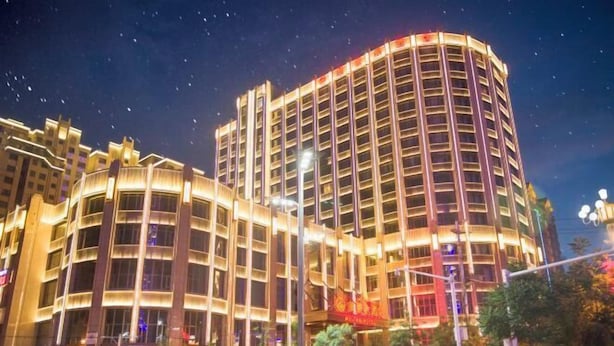 Un hôtel à plusieurs étages, doté d’une façade incurvée et illuminé d’une lumière chaleureuse.