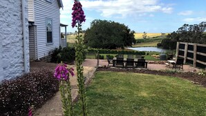 A house with a garden patio, a pond, and a view of the countryside.