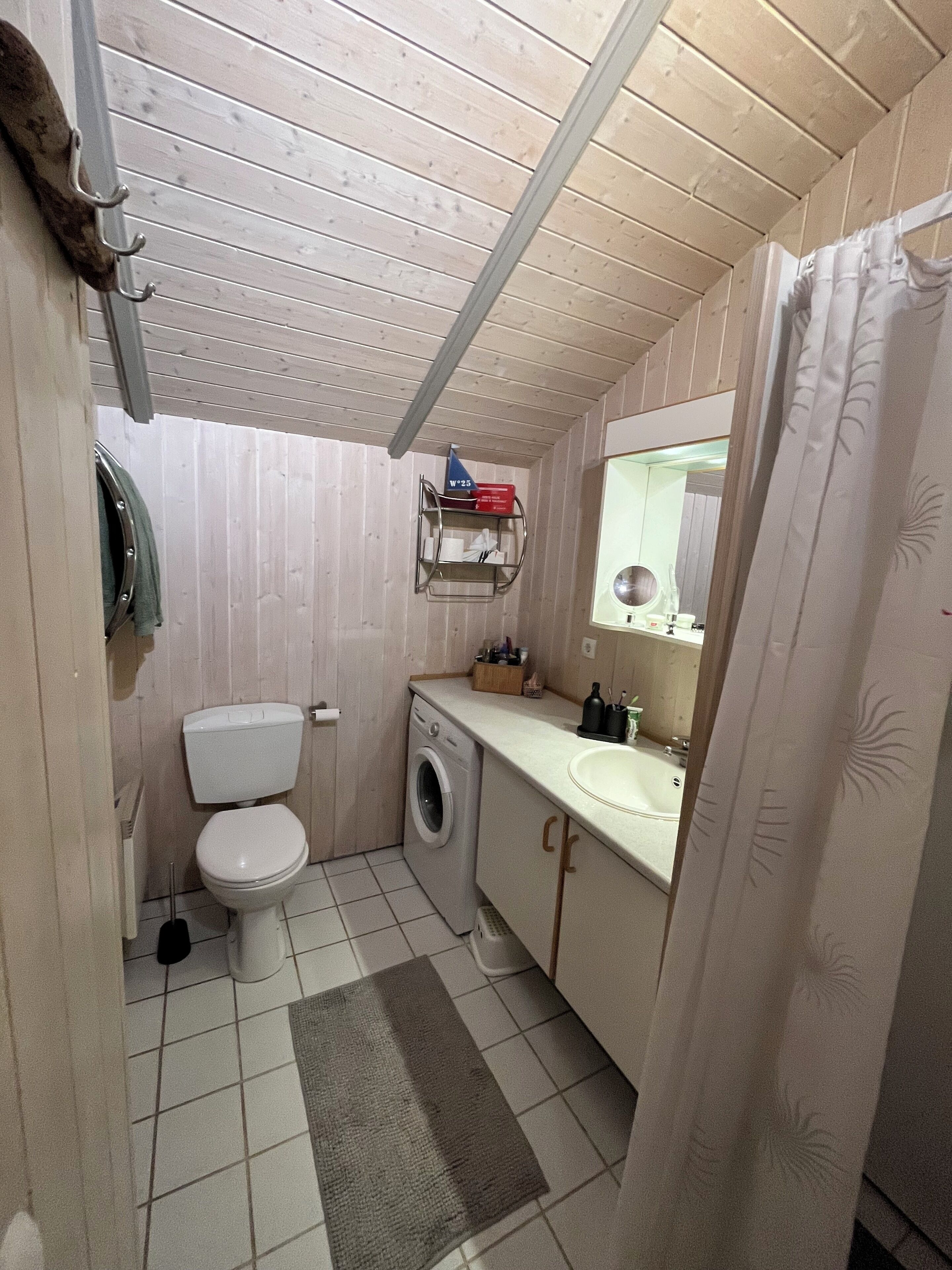 Et lille badeværelse med toilet, vaskemaskine og håndvask.