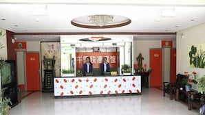 A hotel reception area with a modern design, featuring a reception desk, a chandelier, and a large painting on the wall. - Qianli Express Hotel (Jiamusi)
