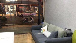 A modern living room with a sofa, a coffee table, and a view of the street outside. - Meitu Huashe Guesthouse (Tongxiang)