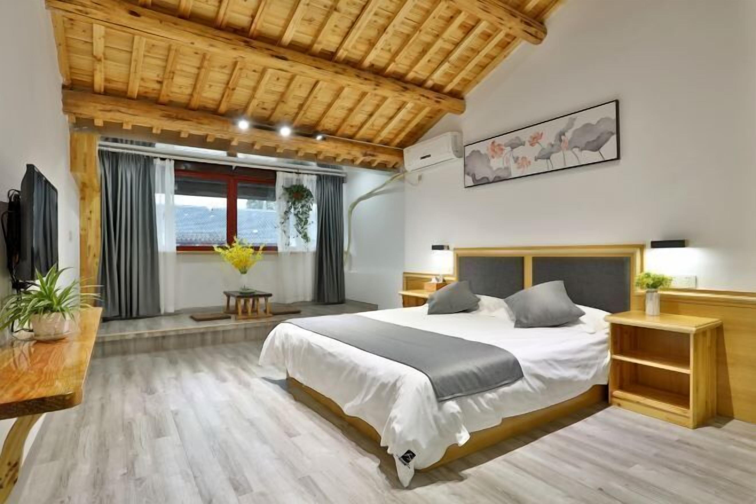 Un dormitorio con techo de madera, cama con ropa de cama blanca, una mesita de noche y una planta.
