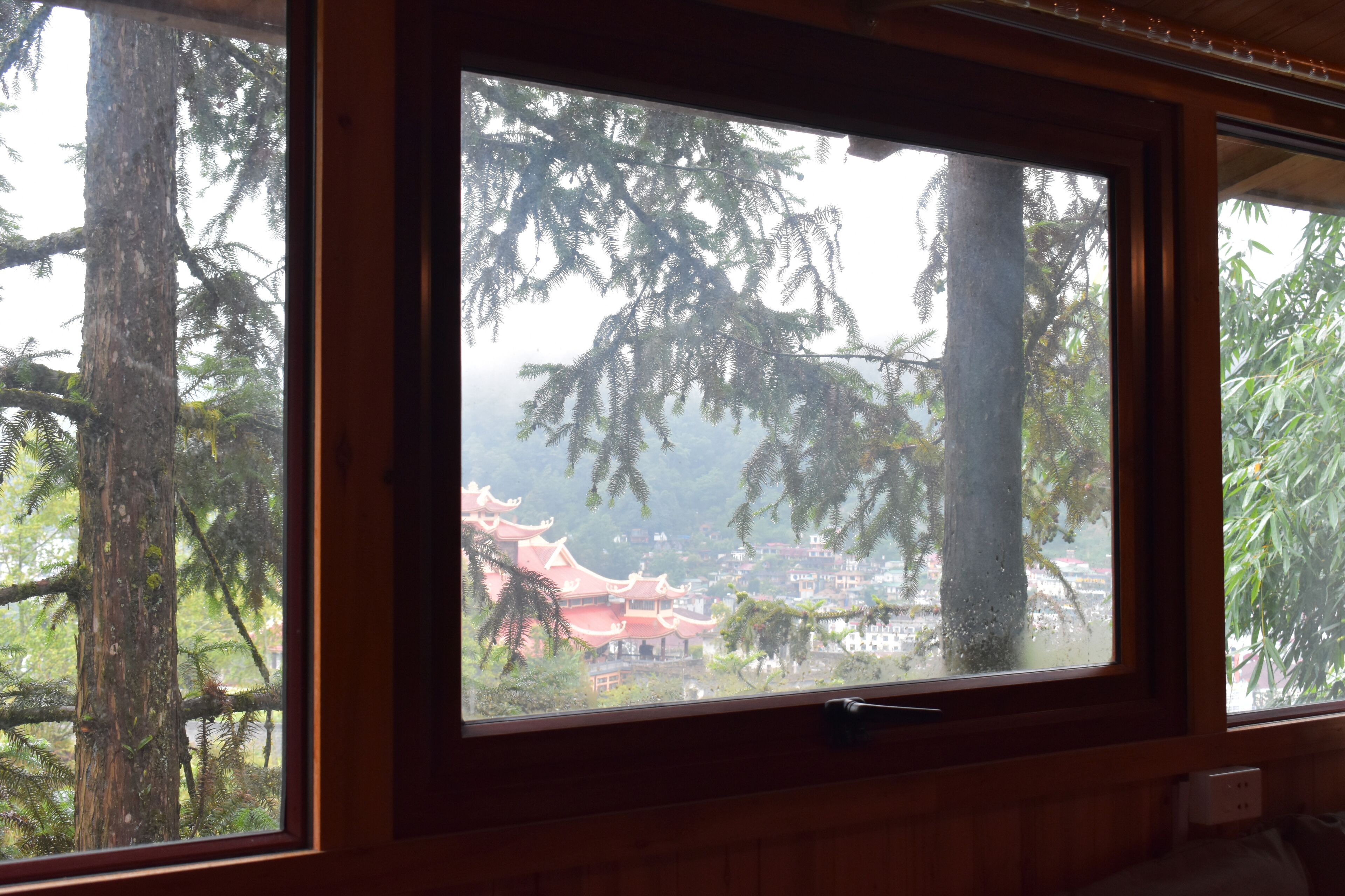 A window with a view of traditional architecture and trees.