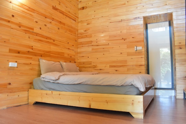 A wooden-paneled room with a bed, a window, and a door. - Sapa Jungle (Sa Pa)