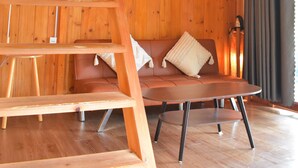 Un interior de madera con escalera de madera, un sofá marrón y una mesa.