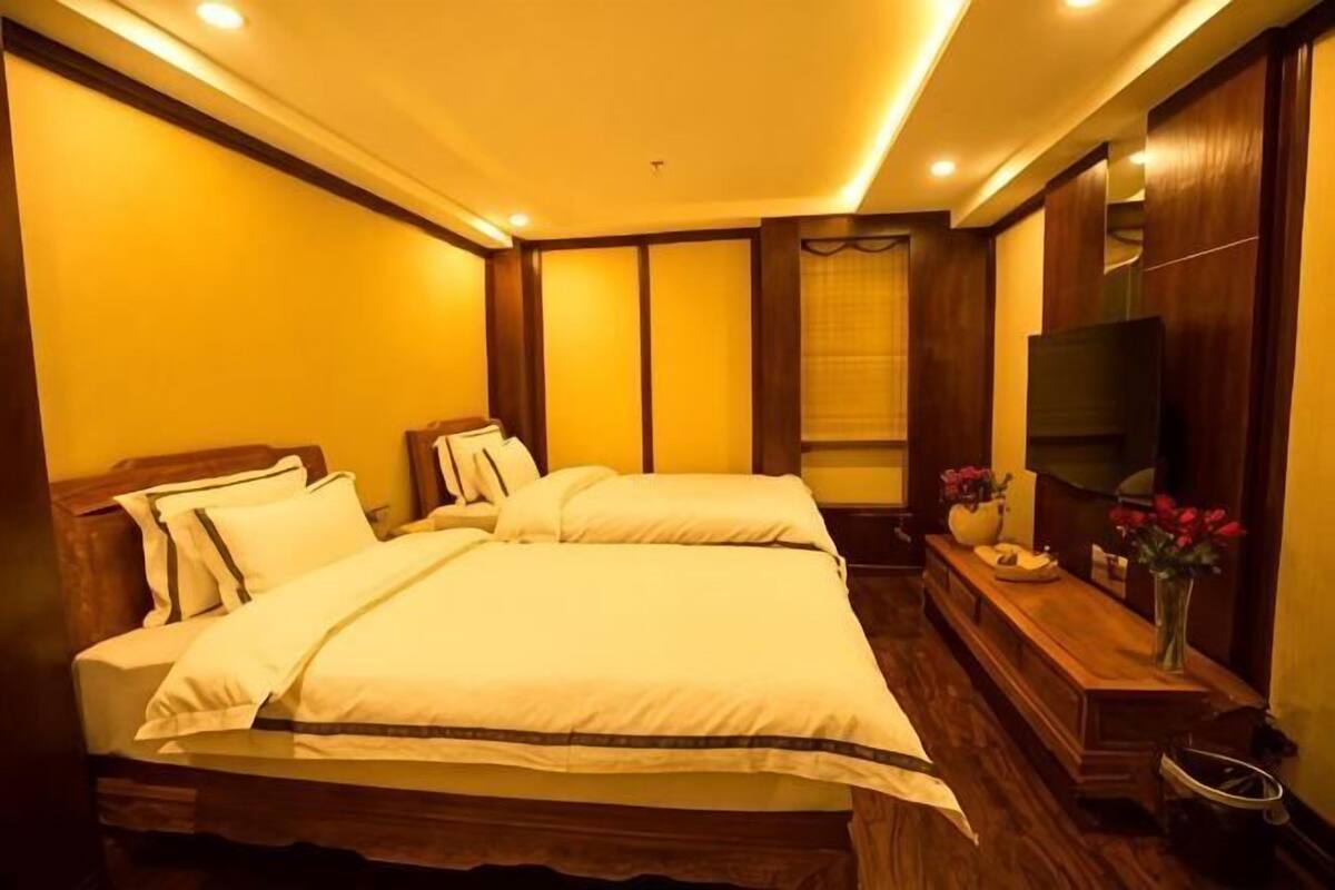 A hotel room with a large bed, a TV, and a wooden dresser.
