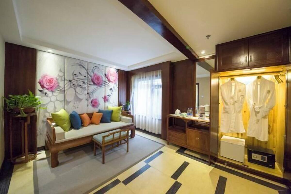 A modern hotel room with a sofa, a large wall art piece, a robe display, and a wooden cabinet.