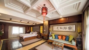 Une chambre de style japonais traditionnel, avec un lit en bois, un canapé agrémenté de coussins colorés et une lanterne décorative.