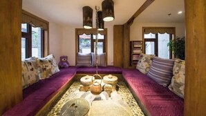 Une pièce chaleureuse avec une fontaine en pierre, des poutres en bois et un canapé violet.